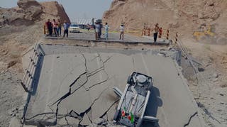 Um carro capotado para em um trecho de uma ponte destruída após um ataque na província de Hormozgan
